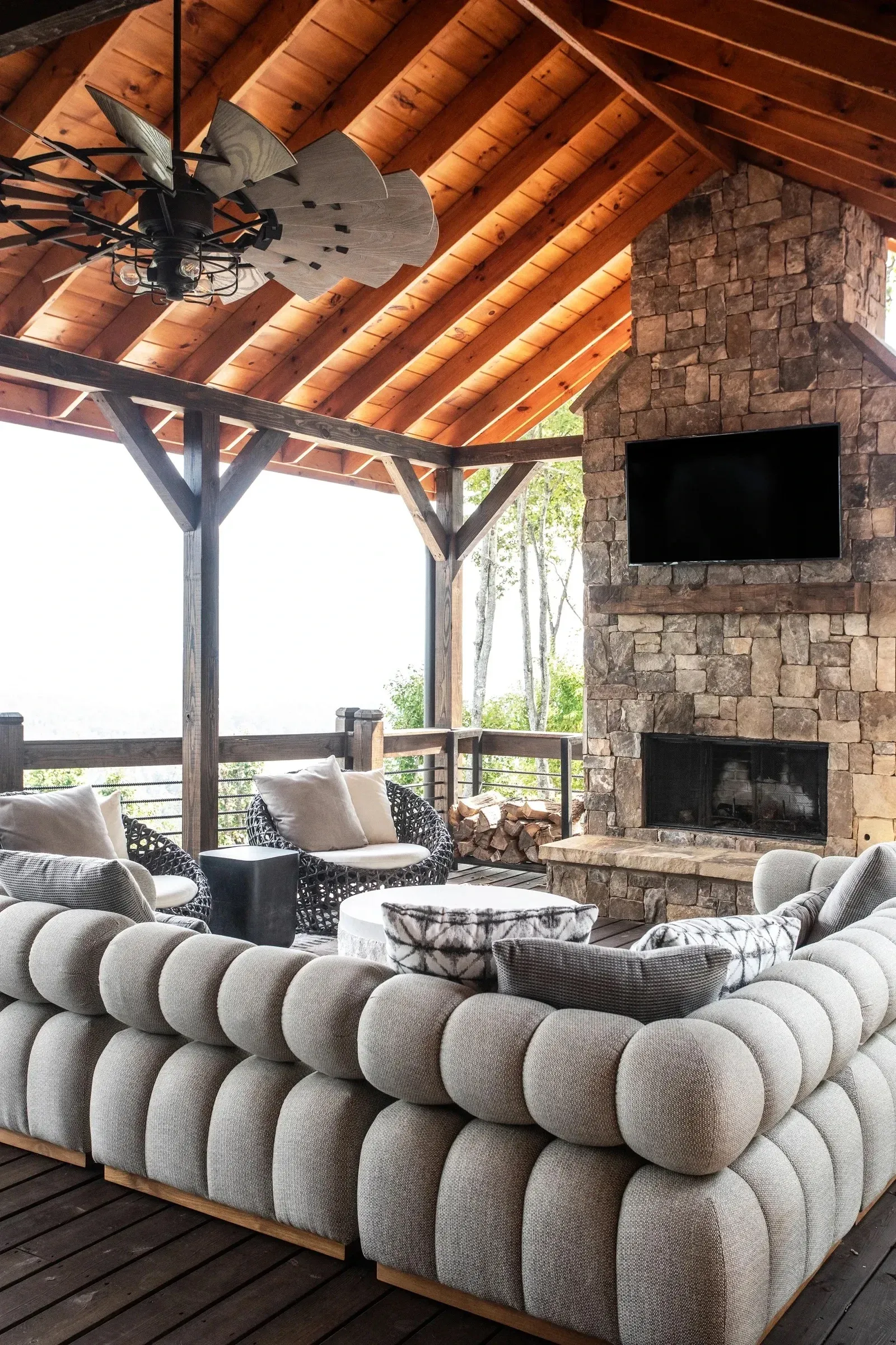 outdoor lounge area with couch, TV, and chimney fireplace